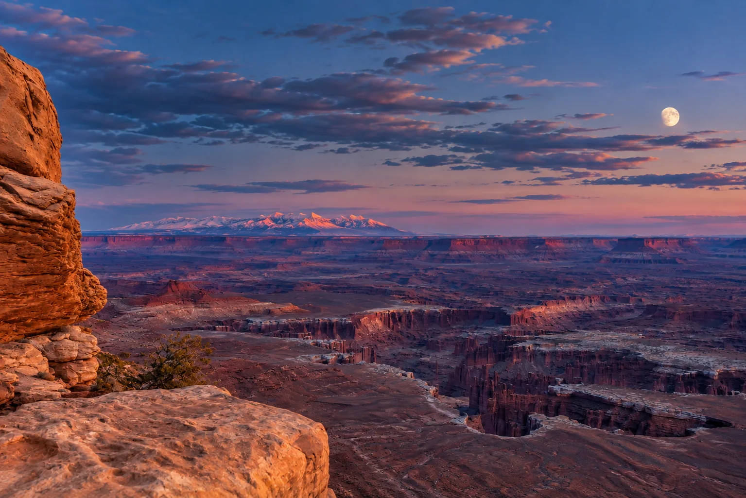 Evening light and a rising moon above the vast red sandstone canyons of Canyonlands.